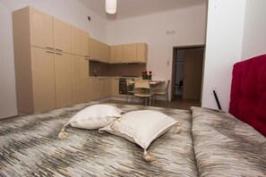 Quarto compacto com cama, cozinha compacta e área de refeições.