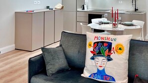 Un apartamento moderno con comedor, kitchenette y un sofá con cojín decorativo.