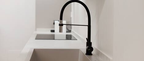 A modern kitchen with a single sink and a black faucet.