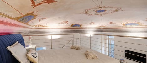 Une chambre d’hôtel avec un lit, une télévision et un plafond orné de motifs artistiques.