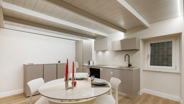 Una cocina moderna con zona de comedor, que incluye una mesa redonda, sillas blancas y un ventanal con vistas.