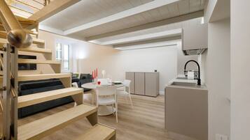 Un intérieur moderne comprenant un escalier, un coin repas et une cuisine.
