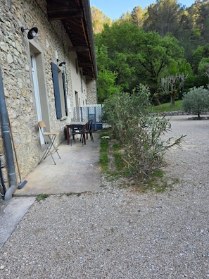 Un edificio in pietra con vialetto sterrato, posti a sedere all'aperto e un piccolo giardino.