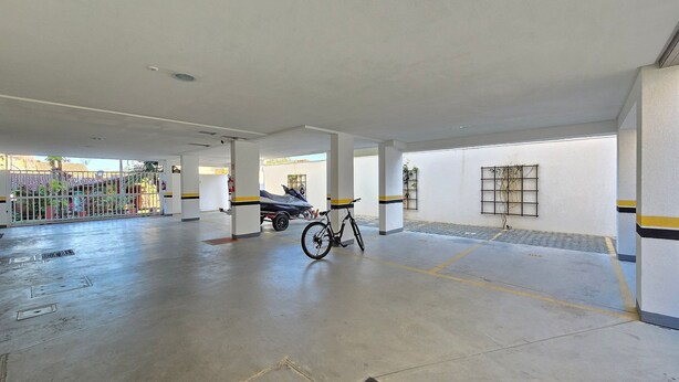 Un'area di parcheggio coperta con pavimento in cemento, colonne e una bicicletta.