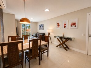 A dining area with a glass-top table, wooden chairs, and a pendant light. - Porto Fino by LikeHome  (Bombinhas)