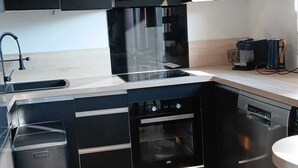 Uma cozinha moderna com armários pretos, eletrodomésticos de aço inoxidável, forno embutido e lava-louças.