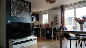 Eine moderne Küche mit integriertem Geschirrspüler, einem großen Flachbildfernseher und einem Essbereich mit Tisch und Stühlen.