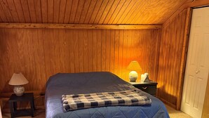 Et soveværelse med en seng, et natbord, en lampe og en dør.