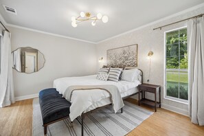 A bedroom with a bed, bedside tables, a mirror, a window with curtains, and a ceiling light fixture. - Savannah Escape - Pool Oasis - Near Tybee & Downtown (Savannah)