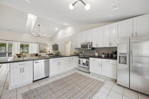 A modern kitchen with white cabinetry, stainless steel appliances, and a large island. - Savannah Escape - Pool Oasis - Near Tybee & Downtown (Savannah)