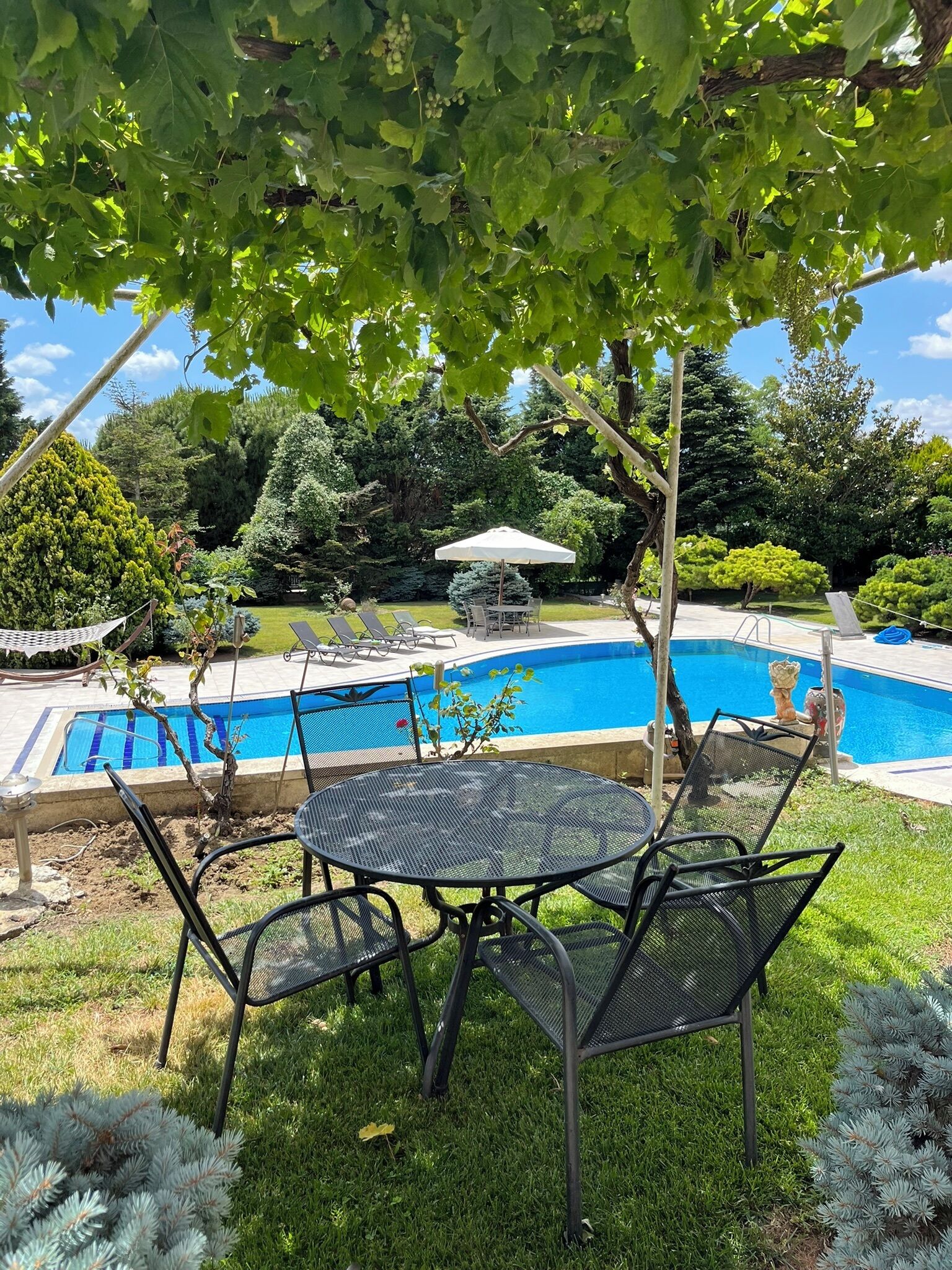 A backyard with a swimming pool, a round metal table, and chairs.