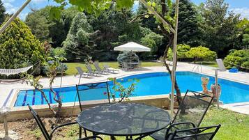 A backyard with a swimming pool, a round metal table, and chairs.