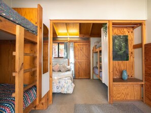 A compact room with bunk beds, a small bed, and a painting on the wall.