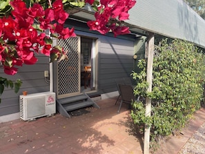 A residential property with a covered porch, an air conditioning unit, and a green bush. - Spear Creek Holiday Park (Woolundunga)
