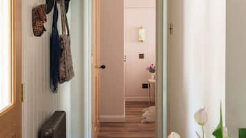 Un couloir avec un radiateur, un tapis à motifs et des chapeaux accrochés au mur.