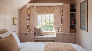A bedroom with a built-in window seat, bookshelves, a bed with pillows, and a framed picture on the wall. - Stylish Sydney Wharf | Free Parking | Sleeps 4 (Bath)