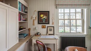 A room with a white desk, bookshelves, a radiator, and a window with a view of buildings. - Stylish Sydney Wharf | Free Parking | Sleeps 4 (Bath)