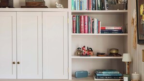A cozy reading nook with a chair, a small table, and a bookshelf filled with books. - Stylish Sydney Wharf | Free Parking | Sleeps 4 (Bath)