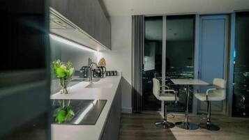 A modern kitchen with a dining area, large windows, and a city view.