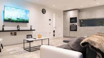 A modern living room with a flat-screen TV, a coffee table, and a sofa.