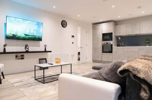 Una sala de estar moderna con una televisión de pantalla plana, una mesa de centro y un sofá.