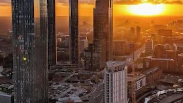 A cityscape with modern high-rise buildings, a river, and a sunset.