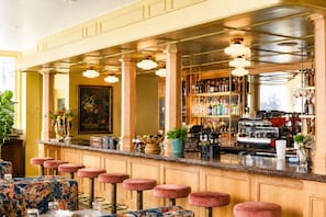 A bar area with a counter, stools, and a variety of bottles and glasses. - The Jardin (Savannah)