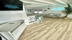 Eine moderne Küche mit einer großen Kochinsel, einem Essbereich mit Stühlen und einer Wand mit einem Neonlichtschild.