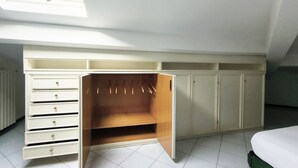 Une chambre avec un puits de lumière, une armoire avec de nombreux tiroirs et un lit.