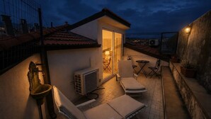 Une terrasse sur le toit avec un petit coin salon, une table et des chaises.