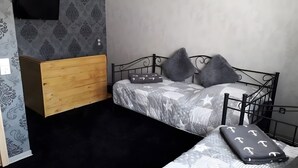 A bedroom with a bed, wooden dresser, and a black floor. - Apartment "1-Zimmer Rhumeblümchen" with Wi-Fi (Rüdershausen)