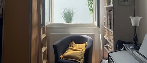 A room with a window, a chair, a desk, and a bookshelf.