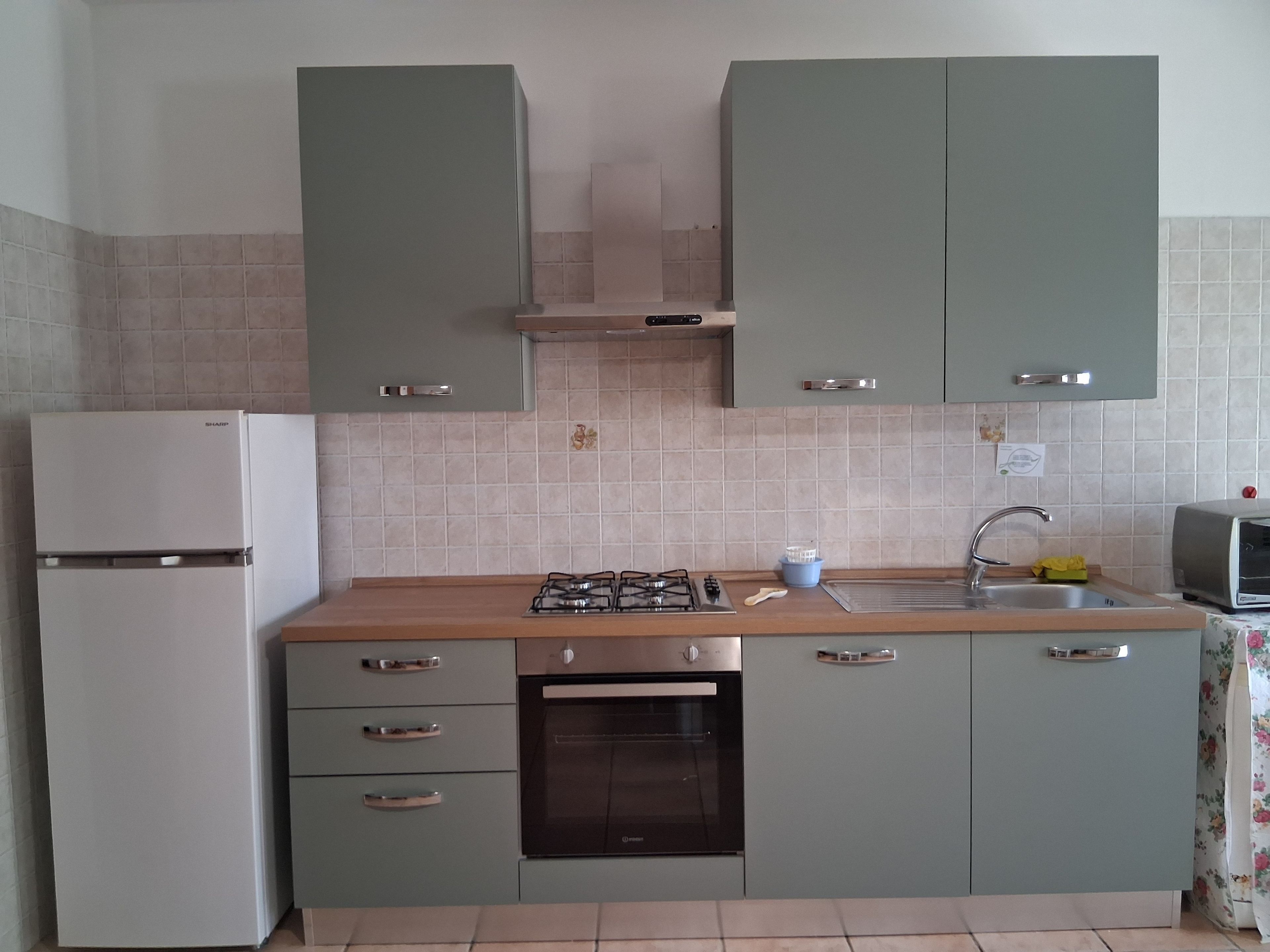 Una cucina con piano cottura a gas, forno, lavello e frigorifero.