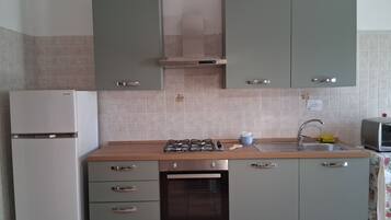 Una cucina con piano cottura a gas, forno, lavello e frigorifero.