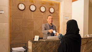 A reception desk with clocks displaying different time zones, a no-smoking sign, and a payment terminal. - Lahdat Al Marwa (Jeddah)
