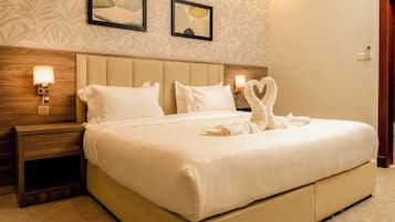 A hotel room with a large bed, two wall-mounted lamps, and a framed artwork above the bed.