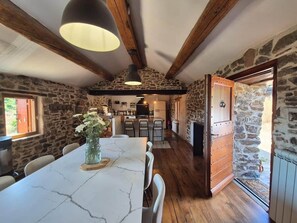 A rustic interior with a marble dining table, stone walls, wooden beams, and a kitchen area. - Nature, waterfall & jacuzzi (Berlou)