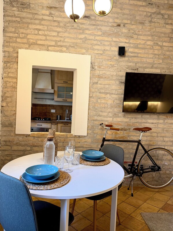 Un coin repas avec un mur en briques, un téléviseur fixé au mur et un vélo.