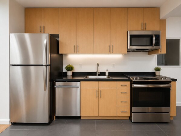 A modern kitchen with stainless steel appliances, wooden cabinets, and a black countertop. - Bright apartment in LiC/Astoria fully equipped with balcony and skyline views (Astoria)
