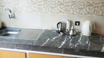 Een koffiezetapparaat/waterkoker, een koelkast, een oven, een kookplaat