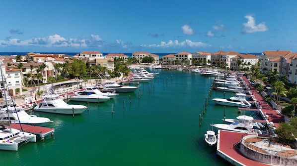 A marina with multiple boats docked, surrounded by buildings with red-tiled roofs.