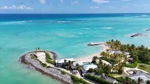 An aerial view of a coastal resort with a beach, a pier, and a rocky shoreline.