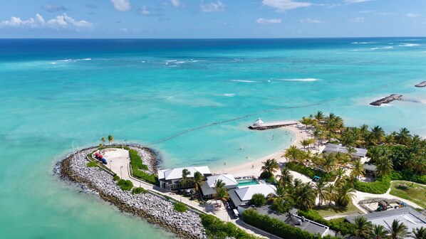 An aerial view of a coastal resort with a beach, a pier, and a rocky shoreline.