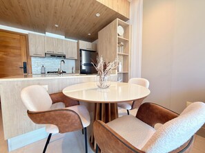 A modern kitchen with wooden cabinets, a central island, and a dining area with plush chairs.