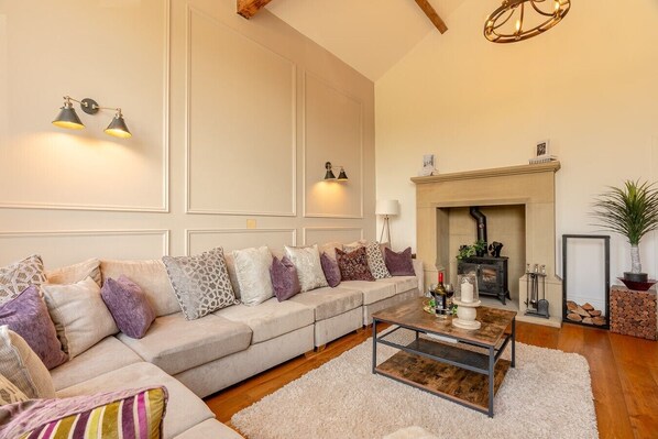 A living room with a sofa, a coffee table, a fireplace, and a wall-mounted light fixture. - The old School House Sleeps 16 (Barnoldswick)