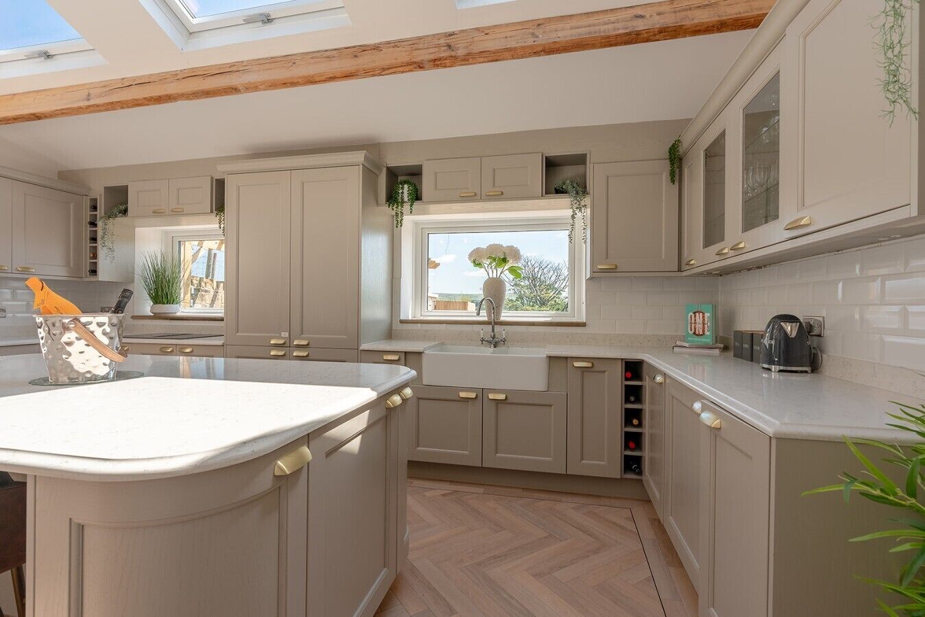 A kitchen with a central island, built-in cabinets, a window with a view, and a herringbone floor pattern.