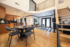 A modern kitchen with wooden cabinets, a dining area with a round table and chairs, and a staircase leading to an upper level. - Spacious Austin Loft, Sleeps 6, with Balcony (Austin)