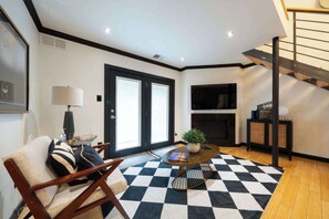 Ein modernes Wohnzimmer mit Schachbrettmuster-Boden, einer Couch, einem Couchtisch, einem Kamin und einer Treppe.