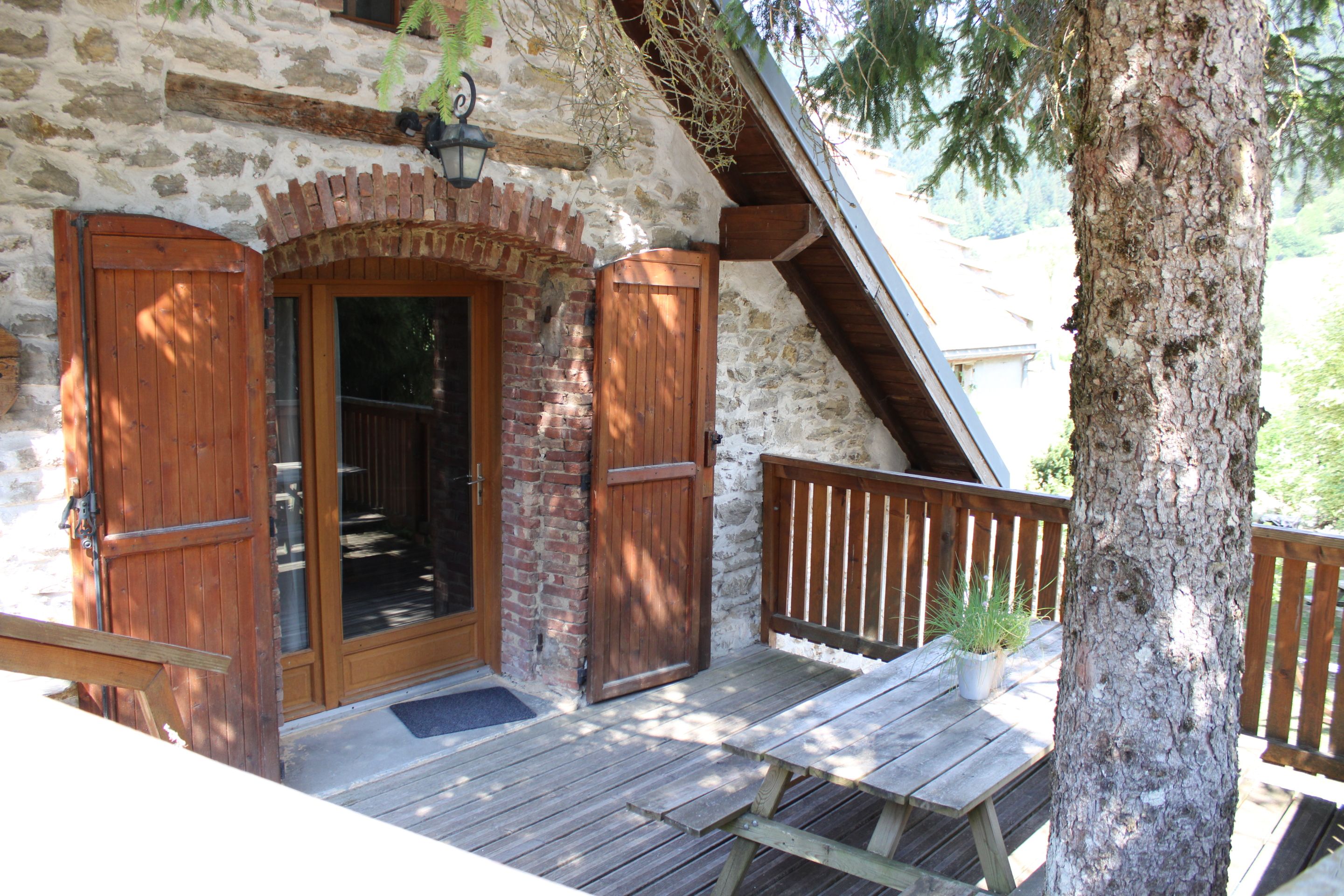 Une cabane rustique en bois, dotée d’une façade en pierre, d’une porte en bois et d’un banc sur le porche.
