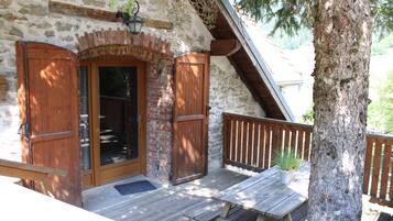 Une cabane rustique en bois, dotée d’une façade en pierre, d’une porte en bois et d’un banc sur le porche.